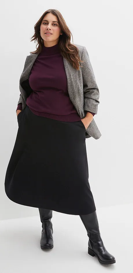 Blazer gris, pull violet et jupe longue noire avec bottes noires.
