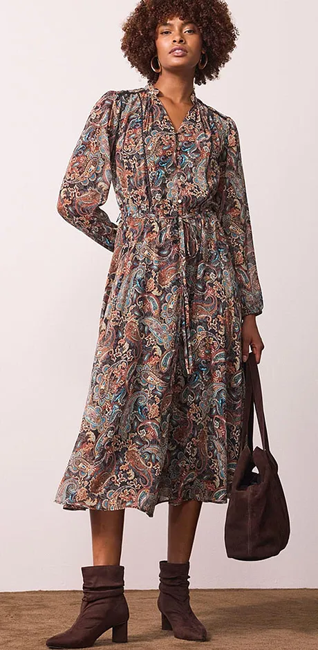 Robe midi imprimée à manches longues, ceinture et décolleté en V. Des bottines marron et un sac à main finalisent la tenue.