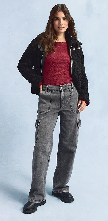 Veste noire, haut rouge, jean large gris et chaussures noires.