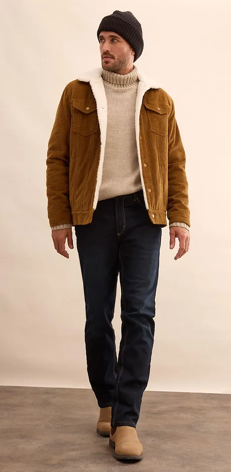 Veste marron, pull à col roulé couleur crème et jean foncé.