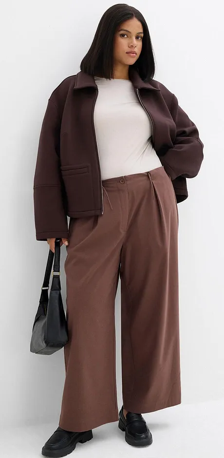 Veste marron, haut clair et pantalon large marron.