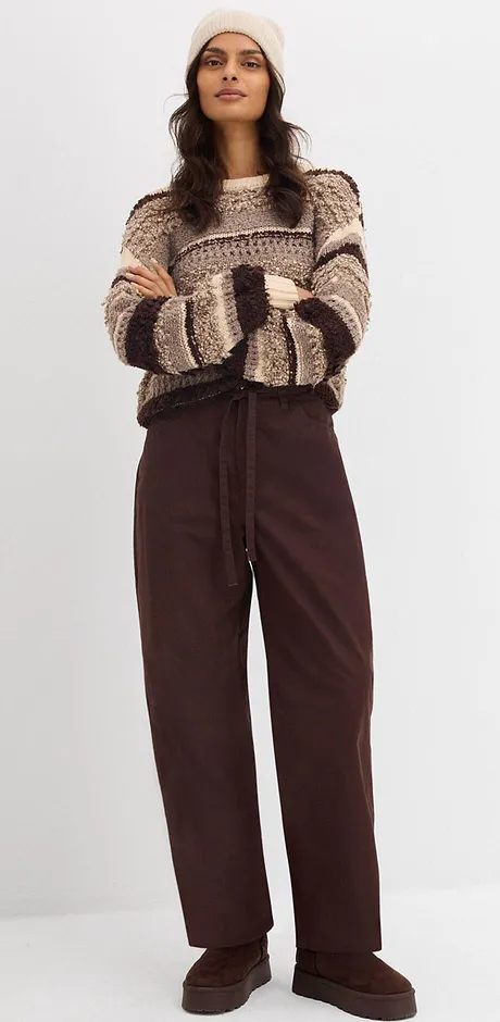 Pull en maille beige et marron avec un pantalon marron.