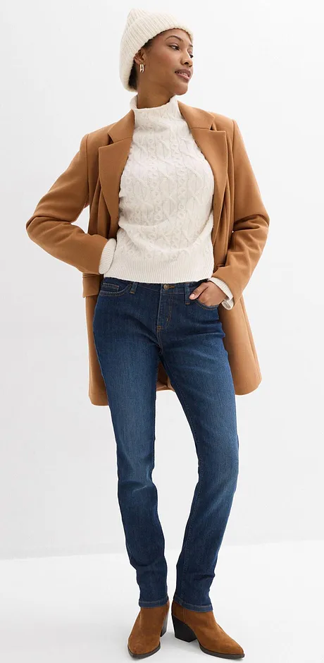 Manteau marron, pull blanc, jean bleu et bonnet.