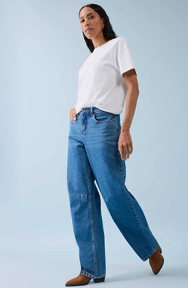 Klassisches weißes T-Shirt kombiniert mit weiten Jeans und braunen Schuhen.