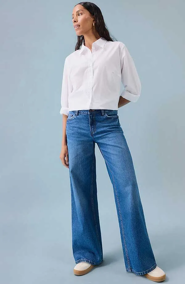 Weißes Hemd zu blauen Jeans mit weitem Bein und weißen Schuhen.