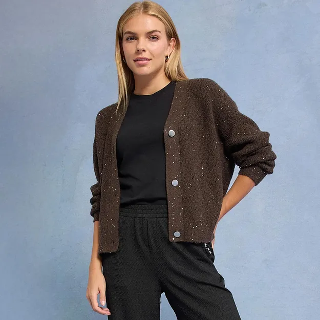Glitzernde braune Strickjacke &uuml;ber schwarzem Outfit.