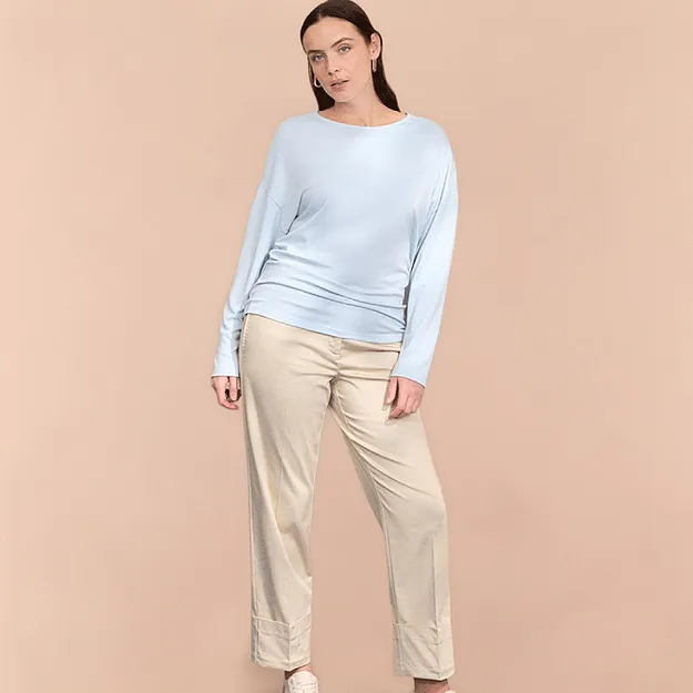 Leichter hellblauer Pullover und beige Hose.