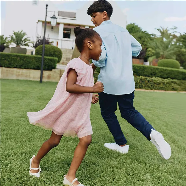 Une petite fille en robe rose s'amuse dans le jardin.