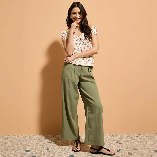 Tenue estivale comprenant un chemisier fleuri, un pantalon large vert et des sandales confortables. 