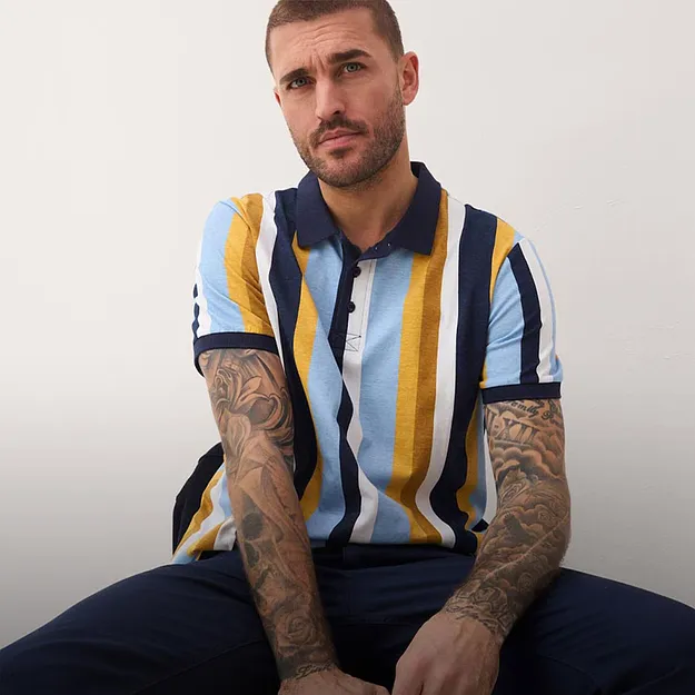 Polo ray&eacute; bleu, jaune et blanc. Pantalon de couleur fonc&eacute;e.