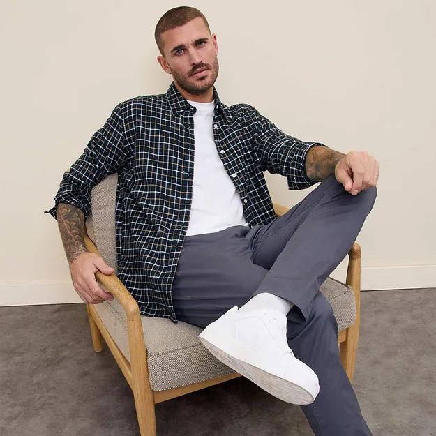 Chemise &agrave; carreaux sur un T-shirt blanc, pantalon gris et sneakers blanches.