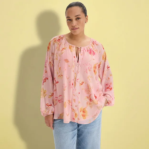 Eine rosa Bluse mit Blumenmuster und lockere Jeans.
