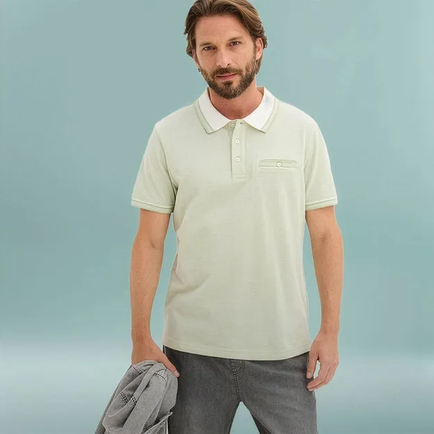 Mann tr&auml;gt hellgr&uuml;nes Poloshirt mit wei&szlig;em Kragen und graue Hose .