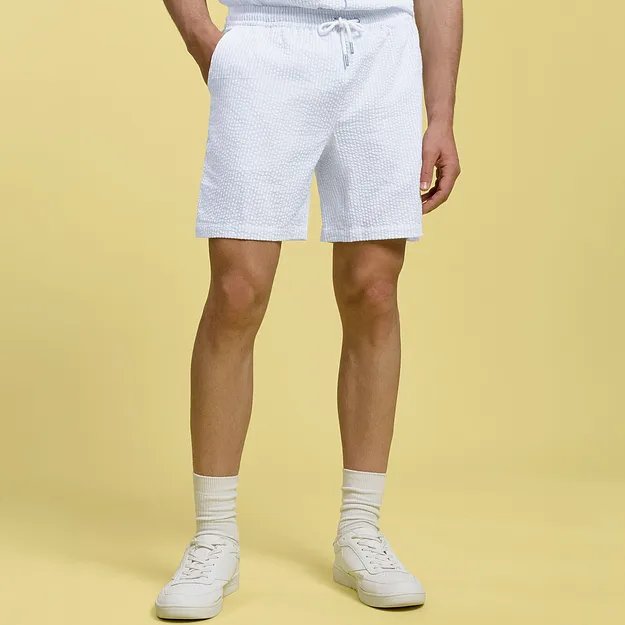 Short blanc avec cordon de serrage, chaussettes blanches et tennis.