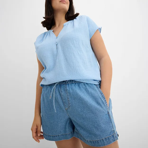 Hellblaues &auml;rmelloses Oberteil mit Rei&szlig;verschluss und lockere Jeans-Shorts in entspanntem Sommerlook.