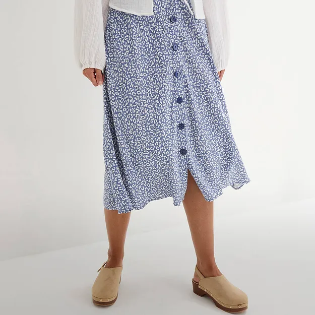 Jupe boutonn&eacute;e bleue &agrave; motifs parfaitement assortie au chemisier blanc et sabots beige.