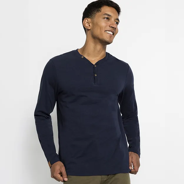 Ein Mann tr&auml;gt ein dunkelblaues Langarmshirt mit Knopfleiste und eine olivgr&uuml;ne Hose.