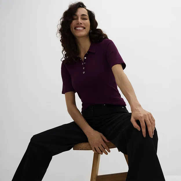 Ein bordeauxrotes Poloshirt mit Kn&ouml;pfen und eine weite schwarze Hose.