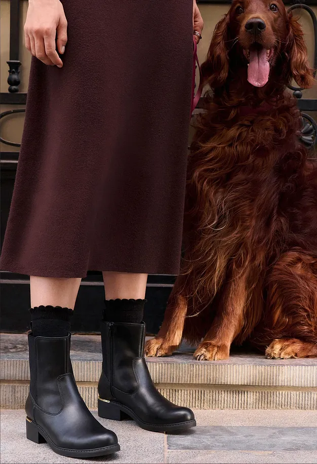 Braunes Kleid, schwarze Socken und schicke schwarze Stiefel mit Goldabsatz.
