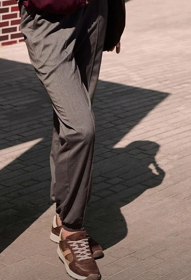 Graue Stoffhose und braune Sneaker definieren den l&auml;ssig-eleganten Look.