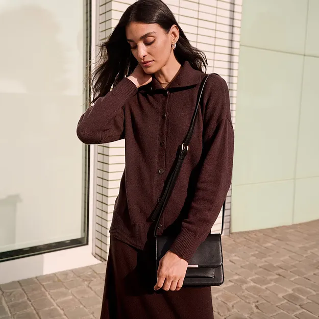 Veste marron &eacute;l&eacute;gante avec col et patte de boutonnage, compl&eacute;t&eacute;e d'un petit sac noir.