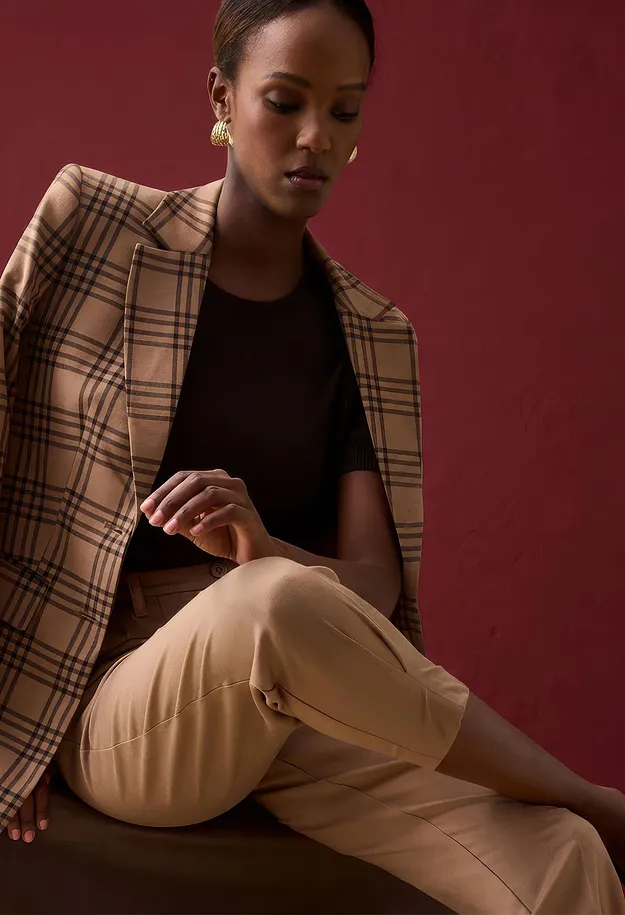 Karierter Blazer, dunkles Oberteil und beige Hose bilden ein elegantes Outfit.