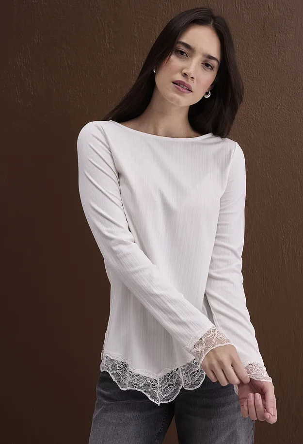 Schickes wei&szlig;es Langarmshirt mit Rippenstruktur und Spitze, kombiniert mit dunklen Jeans.