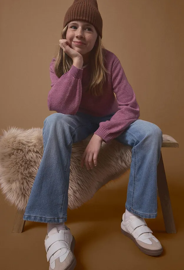 Braune M&uuml;tze, rosa Pullover, blaue Jeans und wei&szlig;e Klett-Sneaker.