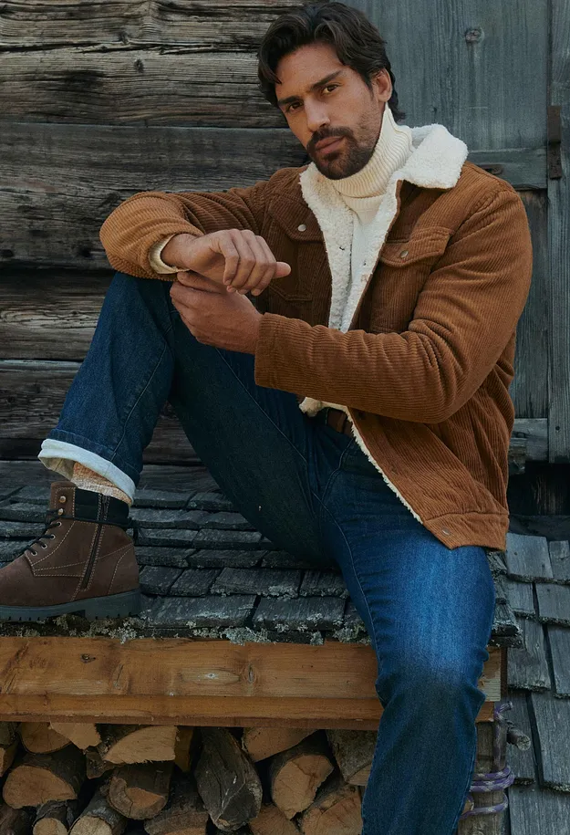 Braune Cordjacke, wei&szlig;er Rollkragenpullover, Jeans und gef&uuml;tterte Boots pr&auml;gen das Outfit.