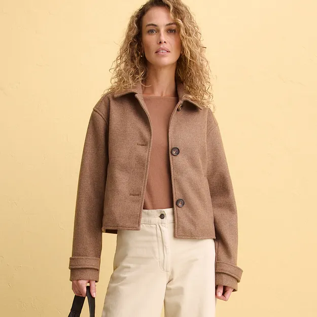 Veste courte &eacute;l&eacute;gante de couleur marron port&eacute;e sur un top raffin&eacute;, et associ&eacute;e &agrave; un pantalon clair.