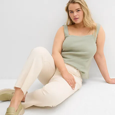 Top vert à larges bretelles, jean clair effiloché à la base et chaussures couleur pastel.