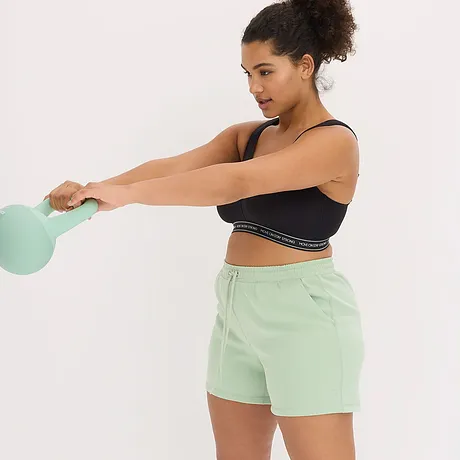 Brassière de sport noire avec bande logo associée à un short vert menthe pour un look sportif rafraîchissant.