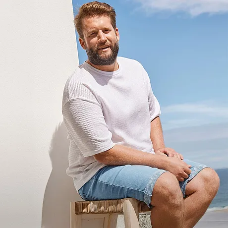 Look estival décontracté : T-shirt blanc et short en jean bleu clair pour une journée détente à la plage.