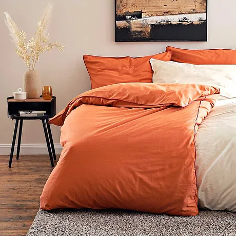 Gemütliche Bettwäsche in warmen Orange- und Cremetönen lädt zum Entspannen ein.