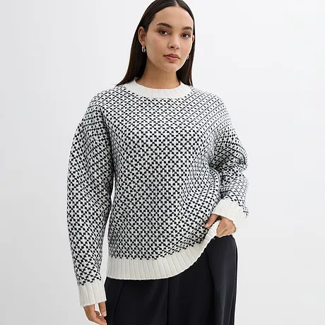 Pull en maille à motif noir et blanc et manches longues.