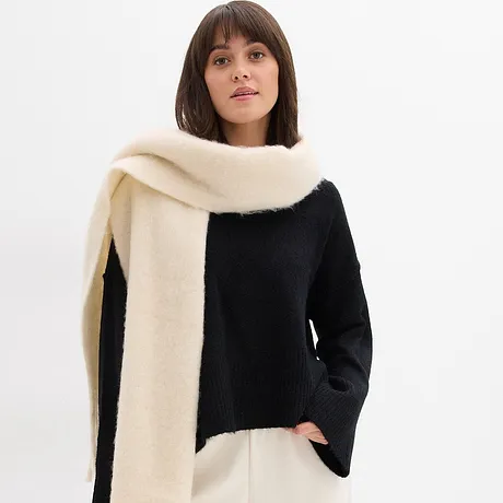 Pull noir associé à une écharpe de couleur crème.