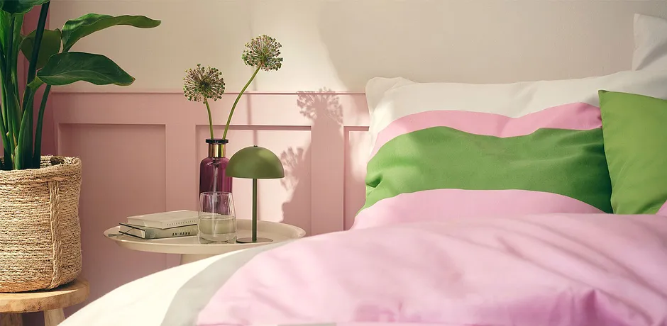 Parure de lit en couleurs pastel rose et vert pour créer un lit cosy dans la chambre ensoleillée.
