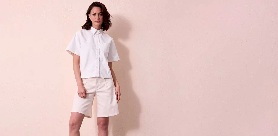 Sommerliches Outfit in Weiß: Kurzärmelige Jeansbluse mit Kragen und knielange Shorts.
