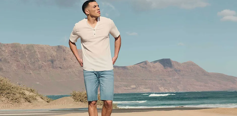 Sommerlicher Look: Helles Kurzarm-Henley-Shirt und hellblaue Jeansshorts. 