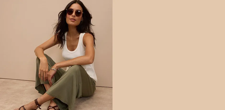 Weißes Tank-Top, olivgrüne Hose und braune Sandalen - ein lässiger Sommerlook mit Sonnenbrille.