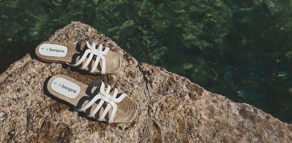 Une paire de sandales blanches sur un rocher au bord de l'eau.