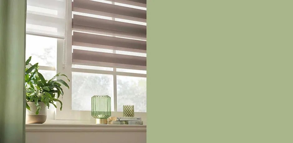 Stores plissés discrets dans des tons terreux. La déco dans des tons verts et les plantes d’intérieur créent une ambiance naturelle.