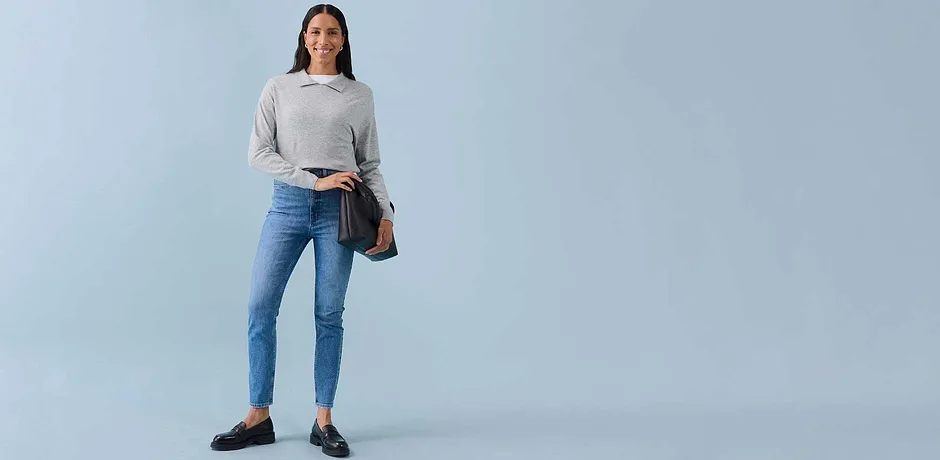 Sweat-shirt gris clair, jean skinny bleu, ballerines foncées et un sac à bandoulière marron.