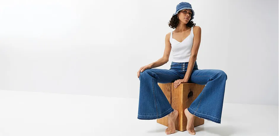 Jean de coupe ample, top blanc et chapeau bleu : le look estival décontracté pour les chaudes journées.