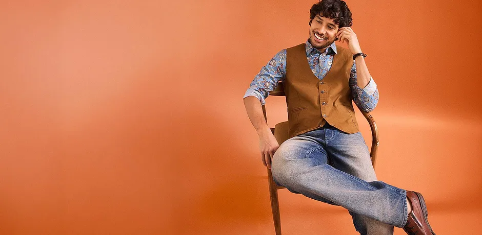 Tenue stylée composée d'un jean, d'une chemise à motifs et d'un gilet marron sans manches.
