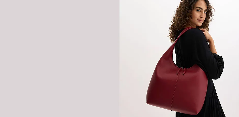 Sac à main extravagant en rouge bordeaux porté sur une tenue noire élégante.