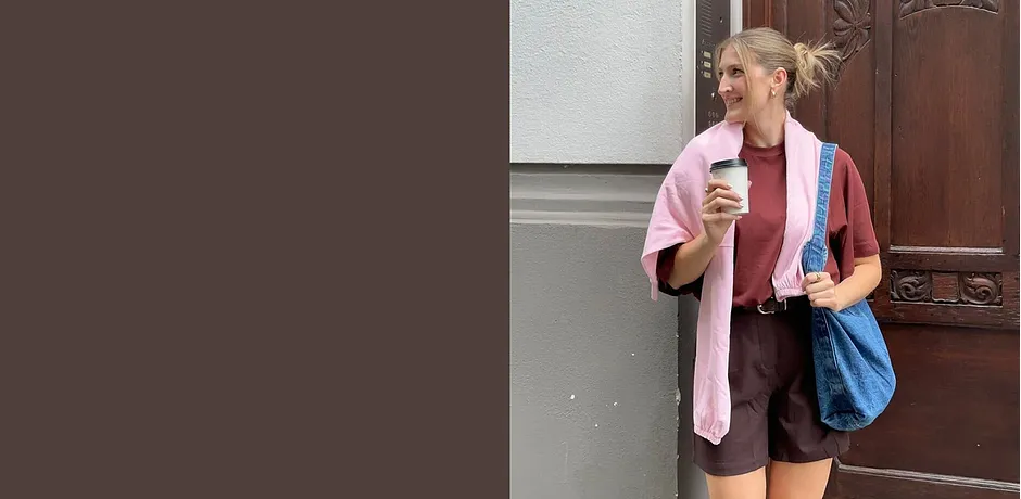 Sommerliches Outfit mit rosa Strickjacke, brauner Shorts und blauer Tasche.