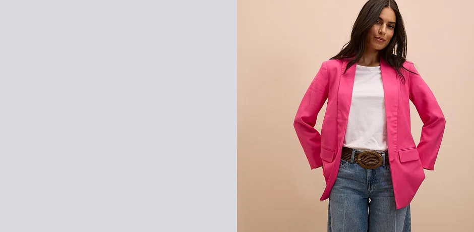 Knalliger pinkfarbener Blazer über weißem T-Shirt, kombiniert mit klassischer Jeans und braunem Gürtel.
