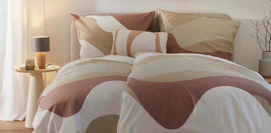 Parure de lit dans des tons terreux, qui s'intègre harmonieusement dans une chambre à l'ambiance cosy.
