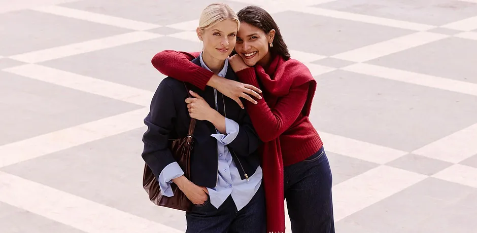 Femme en veste bleue et chemisier à côté d'une autre femme en pull rouge avec écharpe. 